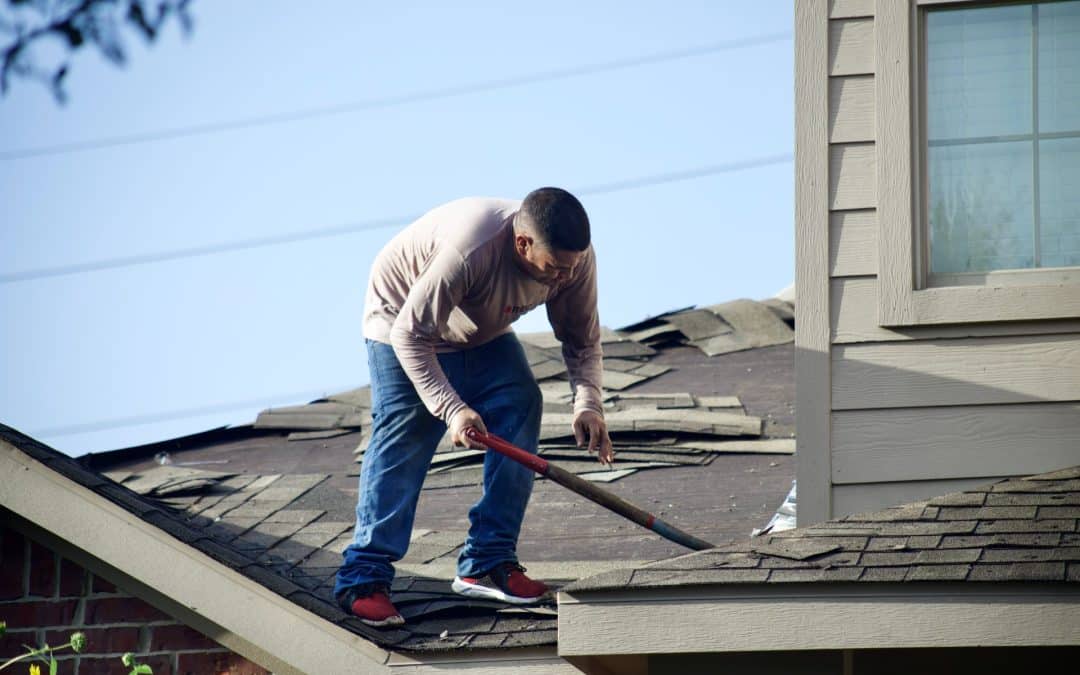 A man stripping shingles from a roof