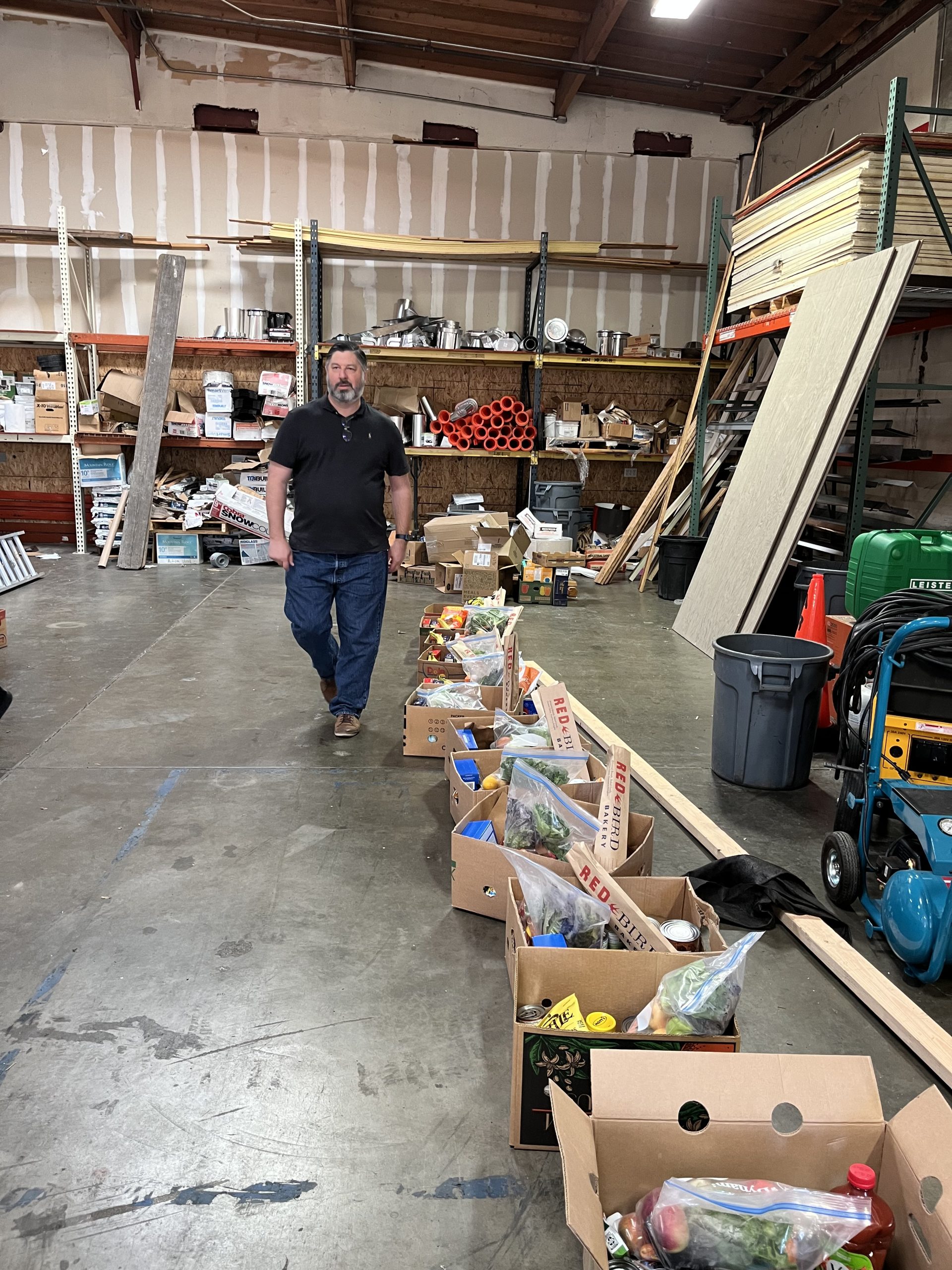 A man standing in a warehouse with boxes of food.