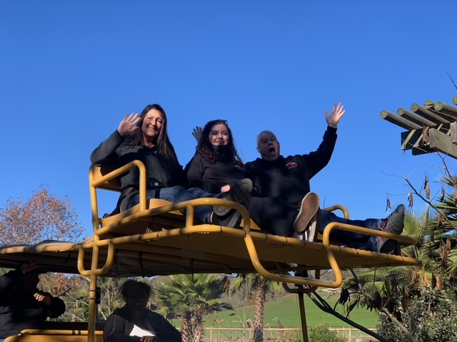 A group of people riding on a yellow truck in a zoo.