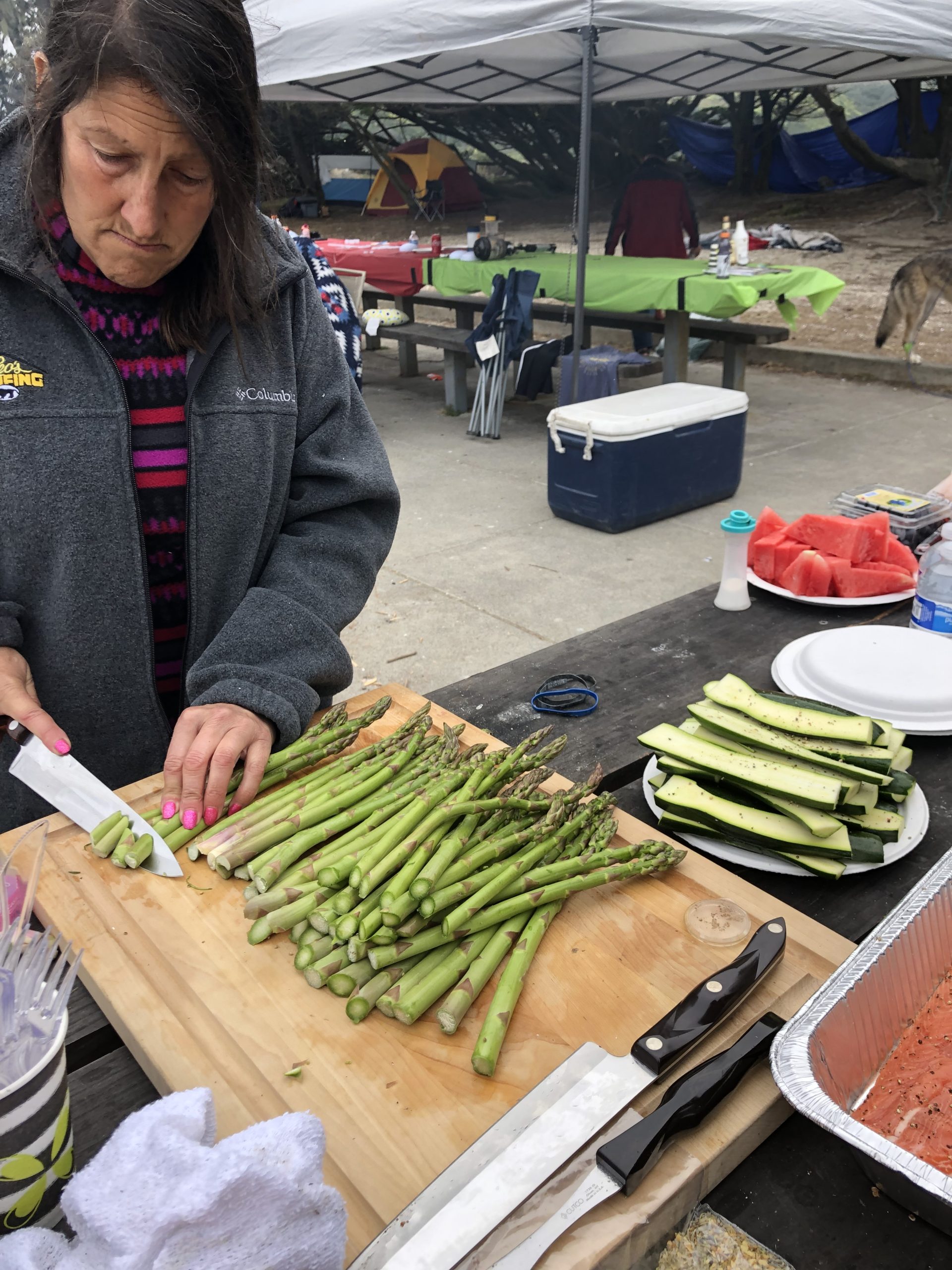 A woman slicing asparagus on a cutting board.