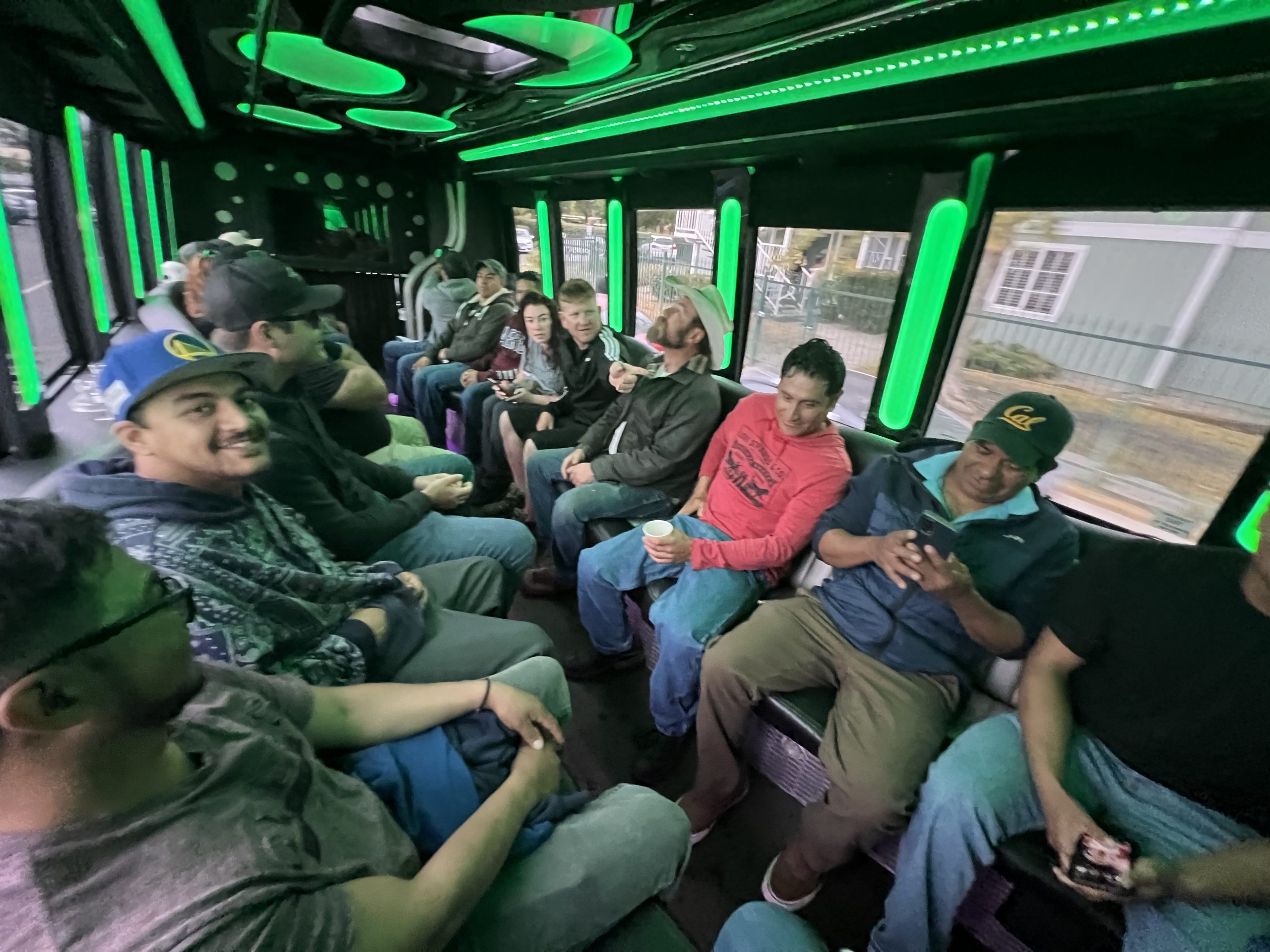 A group of people sitting on a bus with green lights.