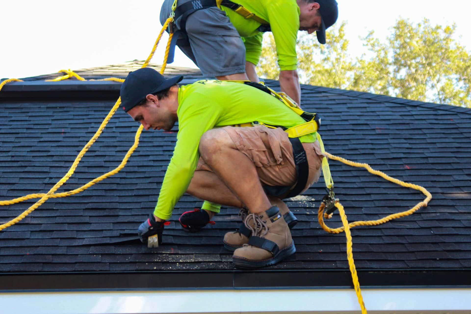 two men in high visibility clothing working on a roof